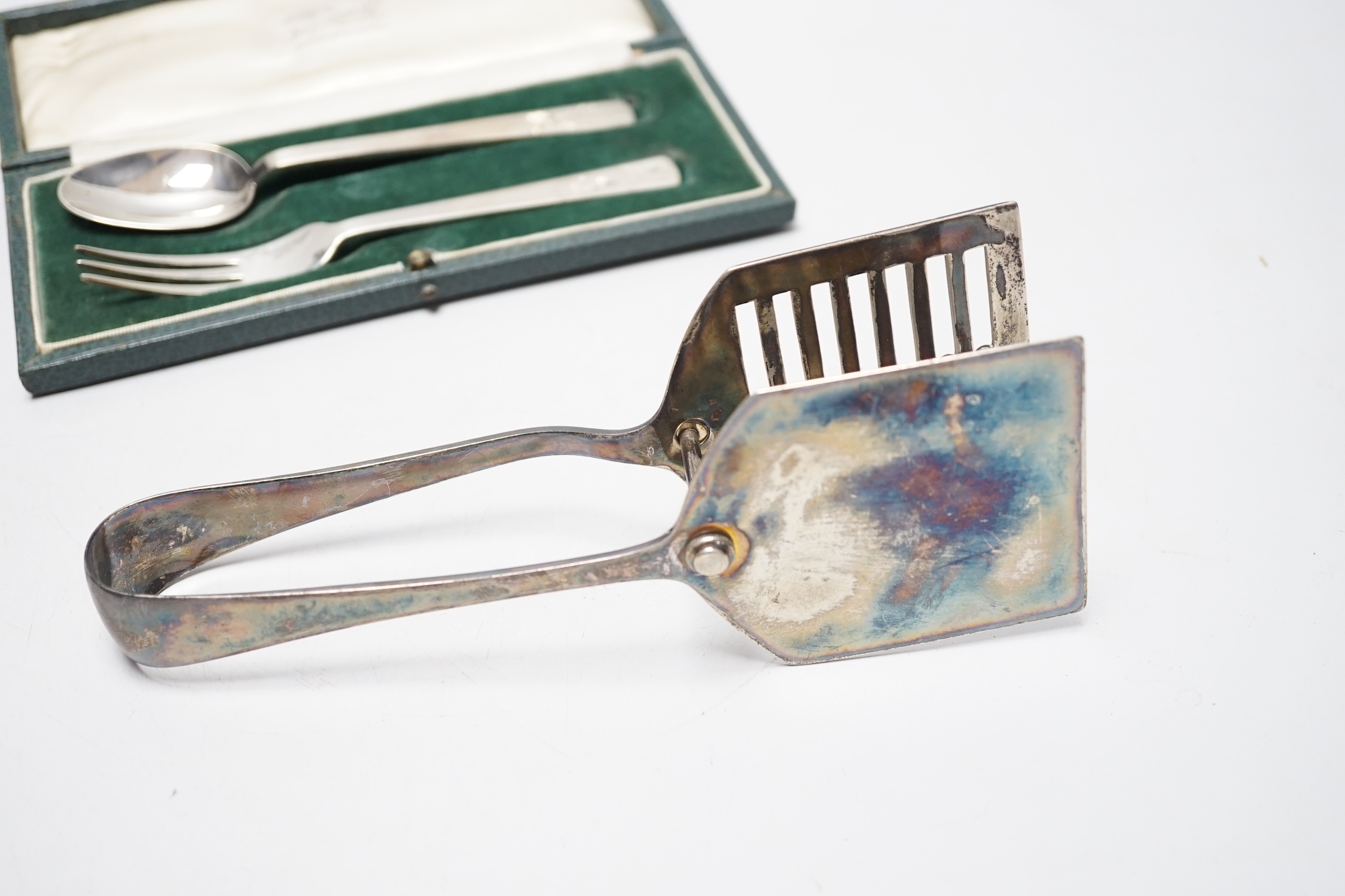 A cased George VI silver christening spoon and fork, by Robert Edgar Stone, London, 1938 and a pair of George V silver asparagus servers.